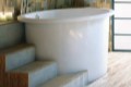 Jacob Soaker Tub Installed with Steps and a Shelf Holding a Deck Mount Tub Filler